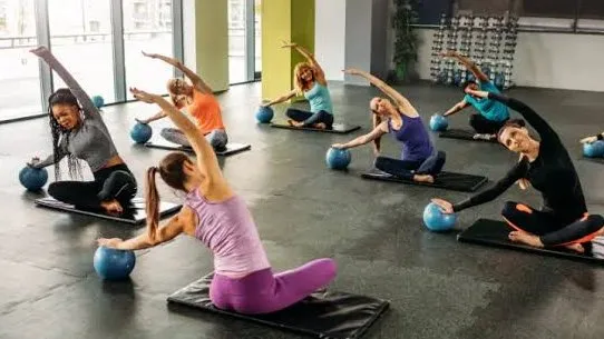 A Pilates class on mats, side-bending over small soft balls
