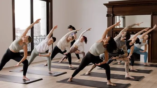 A class in a side angle stretch on mats in a wood-floored studio