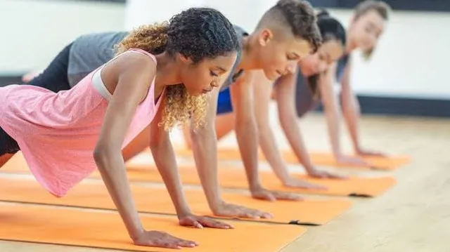 Teenagers holding a plank on orange mats